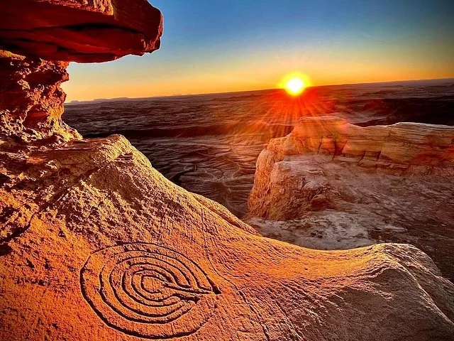 A rock formation with a spiral petroglyph carving at sunset.