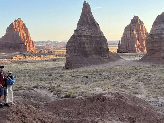 Two people standing in front of towering rock formations at Cathedral Valley.