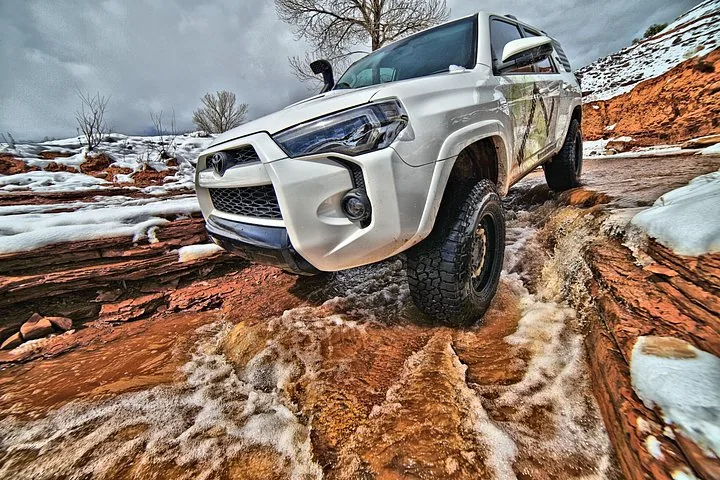 Un Toyota SUV blanco cruzando un vado rocoso y nevado.